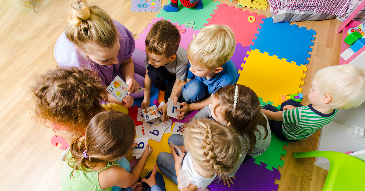 teacher sitting with kids working on flashcards as a group